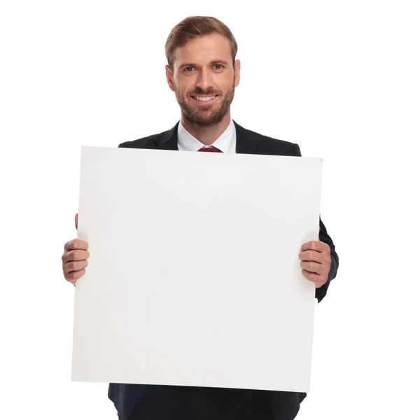 笑みを浮かべて 白い背景の上に立っている間ホワイト ボードを保持しているハンサムな実業家の肖像画 — ストック写真