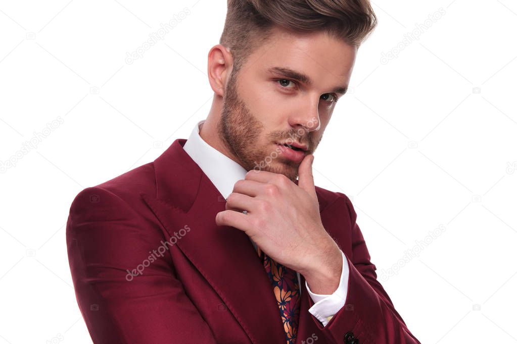 portrait of seductive man in grena suit thinking while standing on white background