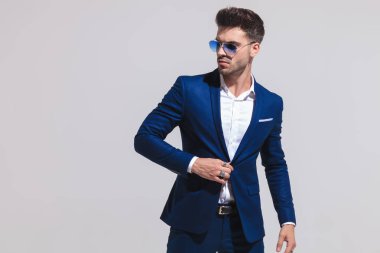 kat'ın düğmesi ve uzak görünüyor gri arka plan üzerinde yan tutarak zarif genç adam