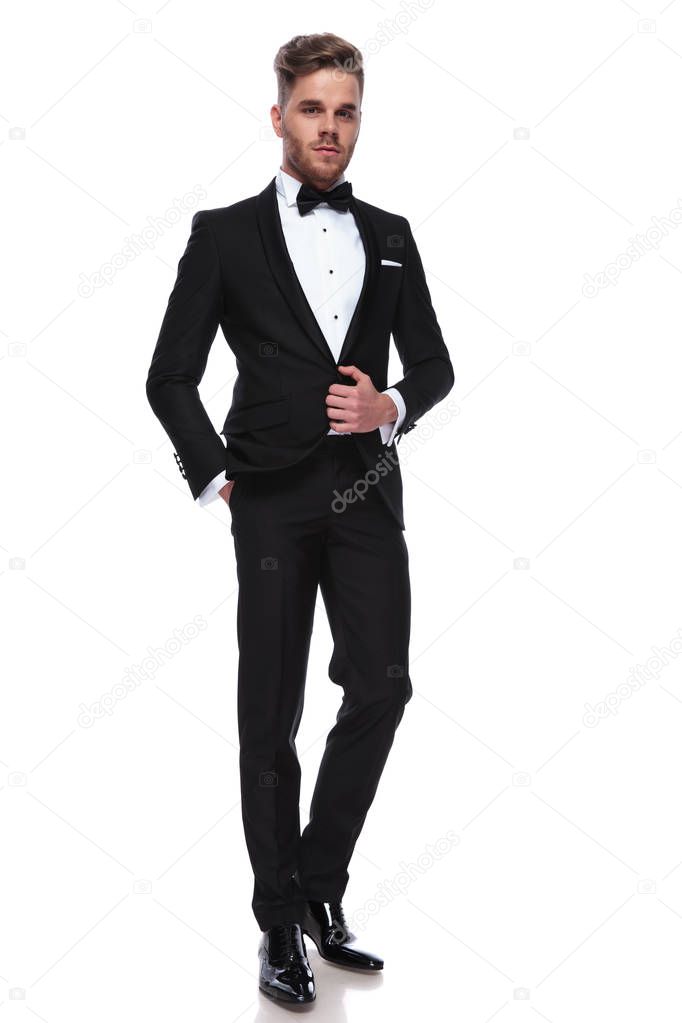 full body picture of a young elegant man in tuxedo , standing on white background