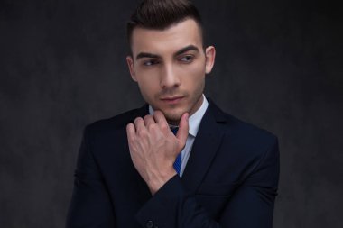 Lacivert takım elbise düşünme ve bakmak için yan duran gri duvar kağıdı arka plan üzerinde giyen meraklı akıllı casual adam portresi