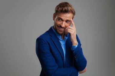 düşünme ve yan ışık gri arka plan üzerinde dururken isteyen mavi elbiseli mutlu akıllı casual adam portresi 