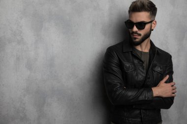 deri ceket gri bir duvar kağıdı yaslanmış iken tarafa bakıyor kendine güvenen adam portresi