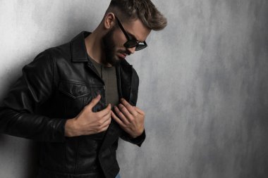 casual adam aşağı bakıyor ve gri bir duvar kağıdı ayakta iken deri ceket kadar düğmelerini portresi