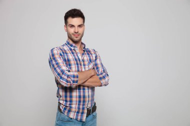 ışık gri arka plan üzerinde katlanmış silah ile ayakta yakışıklı casual adam portresi