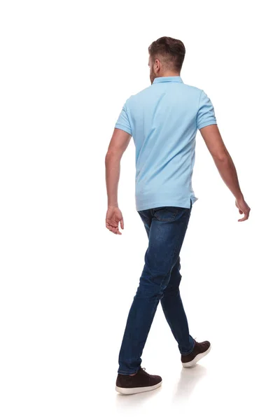 年轻的休闲男子在蓝色马球衫走 并期待在白色的背景 全长图片的一边 — 图库照片