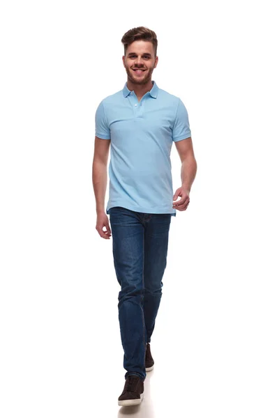 白い背景のフルの長さの画像上前方に青いポロ シャツ ステップを身に着けている魅力的なカジュアルな男性 — ストック写真