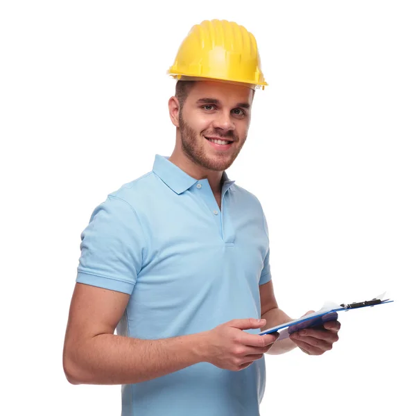 白い背景の上に立っている間青いクリップボードを保持している若いエンジニア学生の肖像画 — ストック写真