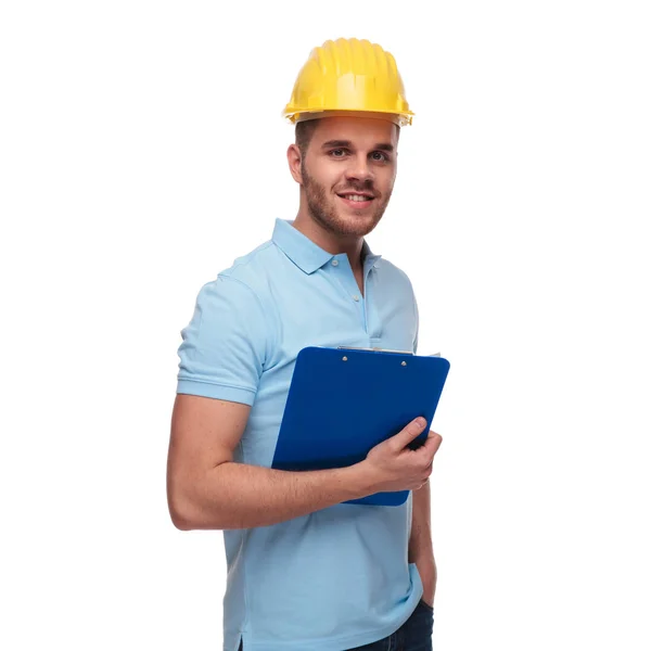 ブルーのポロシャツを着て 白い背景の上に立っている間のポケットを保持しているリラックスしたエンジニアの肖像画 — ストック写真