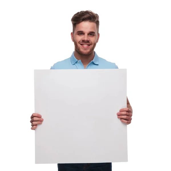 白い背景の上に立っている間空白記号を保持のポロシャツを着てカジュアルな若者の肖像 — ストック写真