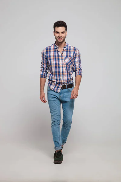 Jovem Homem Bonito Vestindo Jeans Camisa Xadrez Caminha Fundo Cinza — Fotografia de Stock