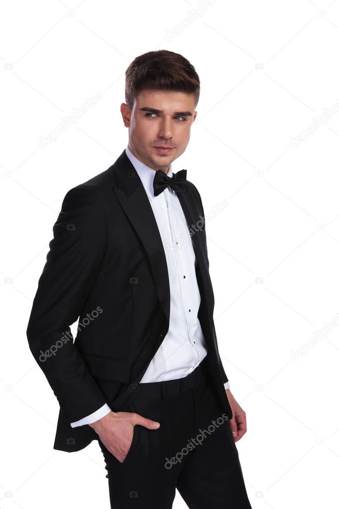 portrait of curious attractive businessman with hand in pocket standing on white background and looking to side