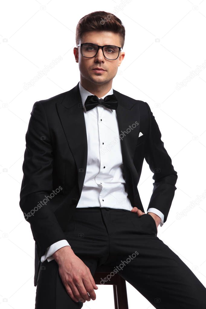 portrait of relaxed businessman wearing sunglasses sitting on wooden chair on white background