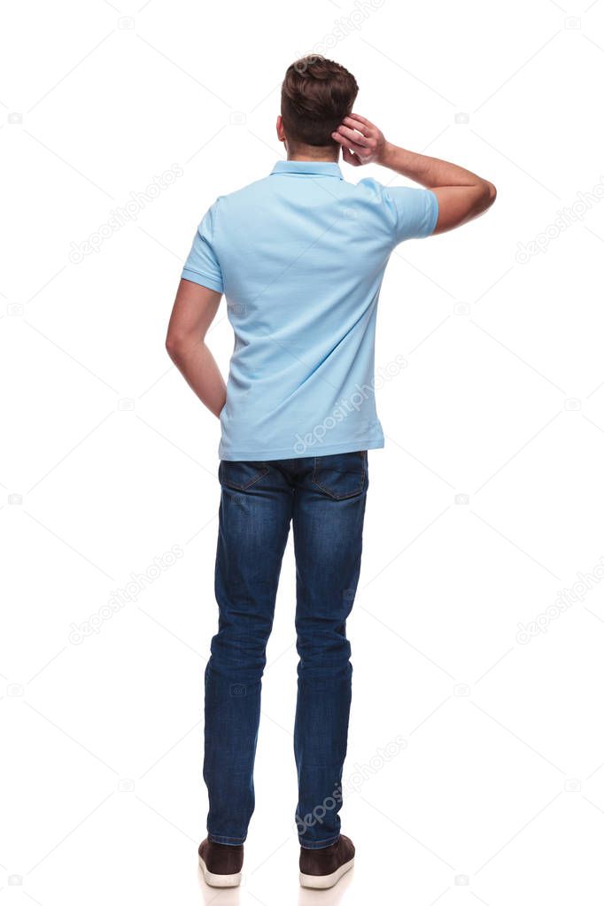 rear view of casual man wearing a blue polo shirt standing on white background with hand in pocket, full body picture