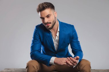 tahta bankta oturan ve avuç içi bir arada tutan seksi smart casual adam portresi