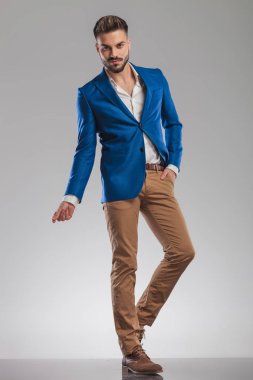 elleri ceplerinde ışık gri arka plan üzerinde duran ve parmaklar, tam boy resmi snapping rahat akıllı casual adam