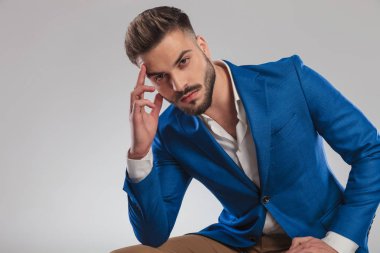 seksi akıllı casual adam ışık gri arka plan üzerinde oturan ve öne, portre resim eğilerek düşünme