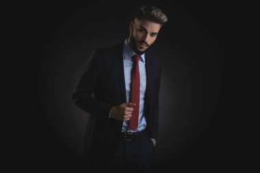 rahat akıllı casual adam Lacivert takım elbise ve siyah arka plan üzerinde kırmızı kravat duran eli cebinde ile portresi