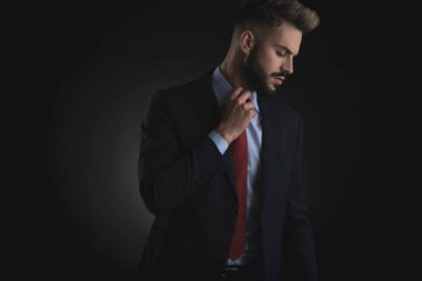 aşağı tarafa bakıyor ve siyah arka plan üzerinde duran kırmızı kravat sabitleme yakışıklı işadamı portresi