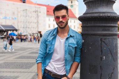 kot gömlek rahat adam aydınlatma direği bir eli cebinde, portre resim ile şehir merkezinde dururken karşı eğilir