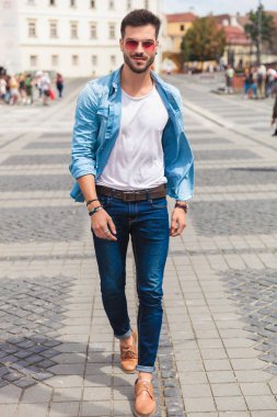 seksi casual adam şehir sokakları ve gülümseyen, tam uzunlukta resim üzerinde yürüme kırmızı güneş gözlüğü takıyor