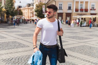 kırmızı güneş gözlüğü takıyor ve kot gömlek gezi kentsel arka plan üzerinde gidiş tutarak seksi casual adam portresi