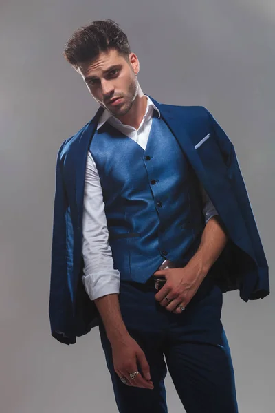 ライトグレーの背景に立っている間ベルトを保持している青いスーツを着て上品な男性の肖像画 — ストック写真