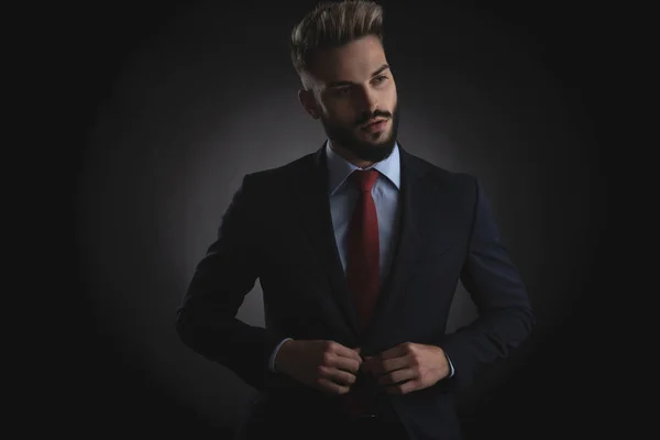 黒の背景の上に立って側を見下ろしながらのネイビー スーツのボタンおさる実業家の肖像画 — ストック写真