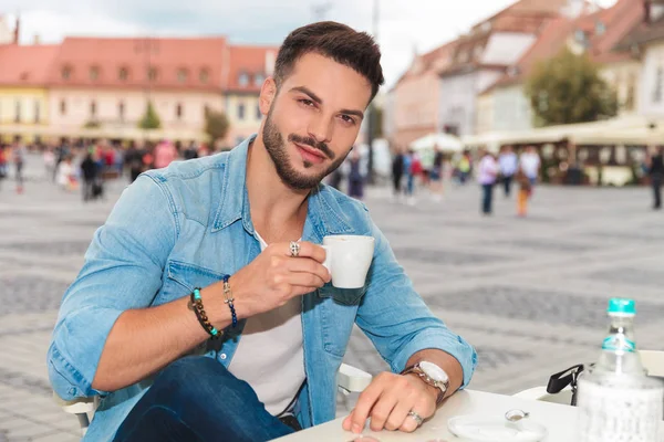 テーブルとコーヒーを飲む 肖像画の絵で街に座っているカジュアルな男の笑みを浮かべてください — ストック写真