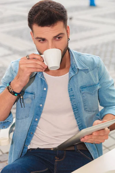 Retrato Jovem Bebendo Café Segurando Tablet Enquanto Sentado Mesa Olhando — Fotografia de Stock