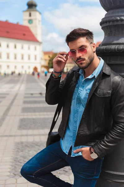 rahat rahat adam aydınlatma direği karşı yaslanmış duran güneş gözlüğü cebinde bir el ile şehirde giderir