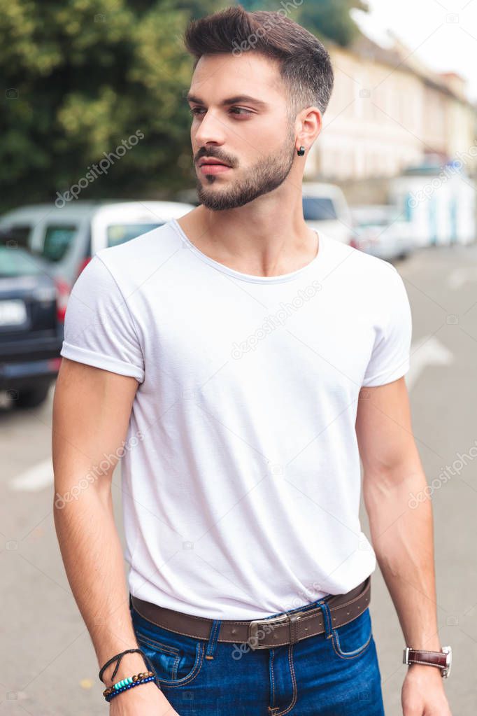 portrait of casual man looking to side while standing on city street