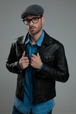 seksi genç adam düz kapaklı deri ceket yaka dururken açık gri renkli, portre resim tutar.