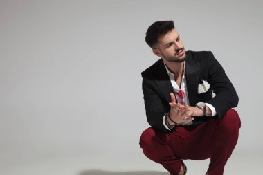 ışık gri arka plan üzerinde çömelme ve birlikte elele süre tarafına arıyorum moda adam portresi