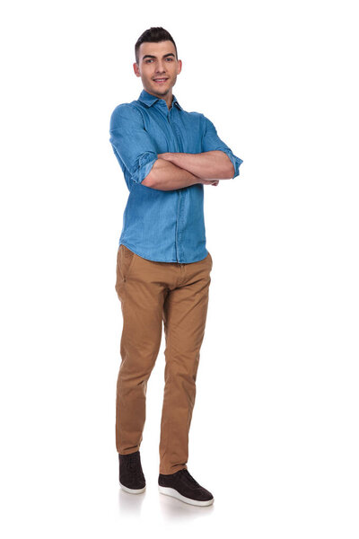 young casual man standing with folded hands on white background and stepping forward