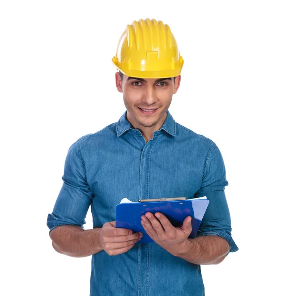 白い背景の上に立っている間青いクリップボードを保持しているハンサムなエンジニア学生の肖像画 — ストック写真