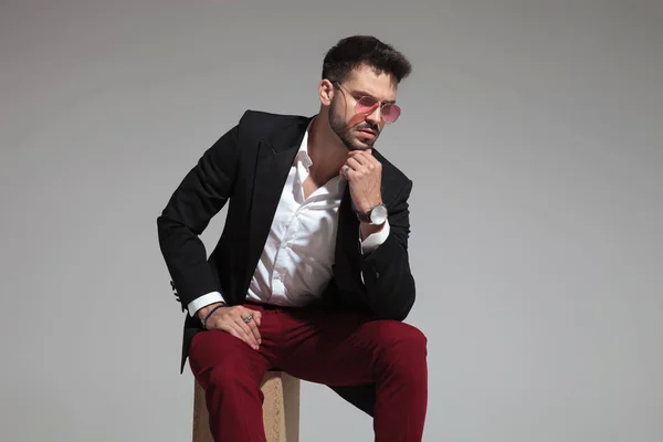 Pensive Smart Casual Man Sitting Wearing Red Sunglasses Black Suit — Stock Photo, Image