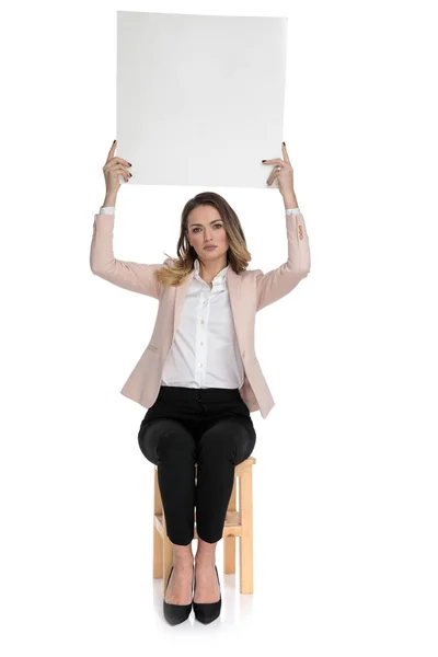 Jovem Empresária Vestindo Saltos Altos Mantém Placa Branca Enquanto Sentado — Fotografia de Stock