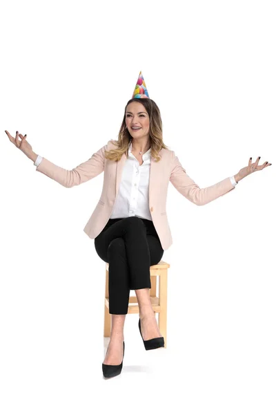 Glad Affärskvinna Med Födelsedag Hatt Gör Välkomnande Gest Samtidigt Sitter — Stockfoto