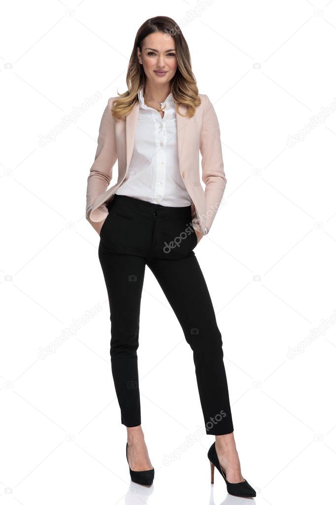attractive businesswoman in pink suit stands on white background and hold pockets, full length picture