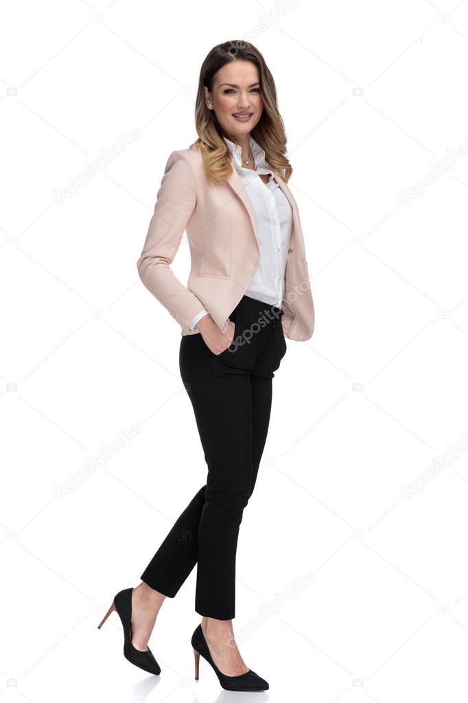 sexy businesswoman steps to side on white background with hand in pocket and smiles, full body picture