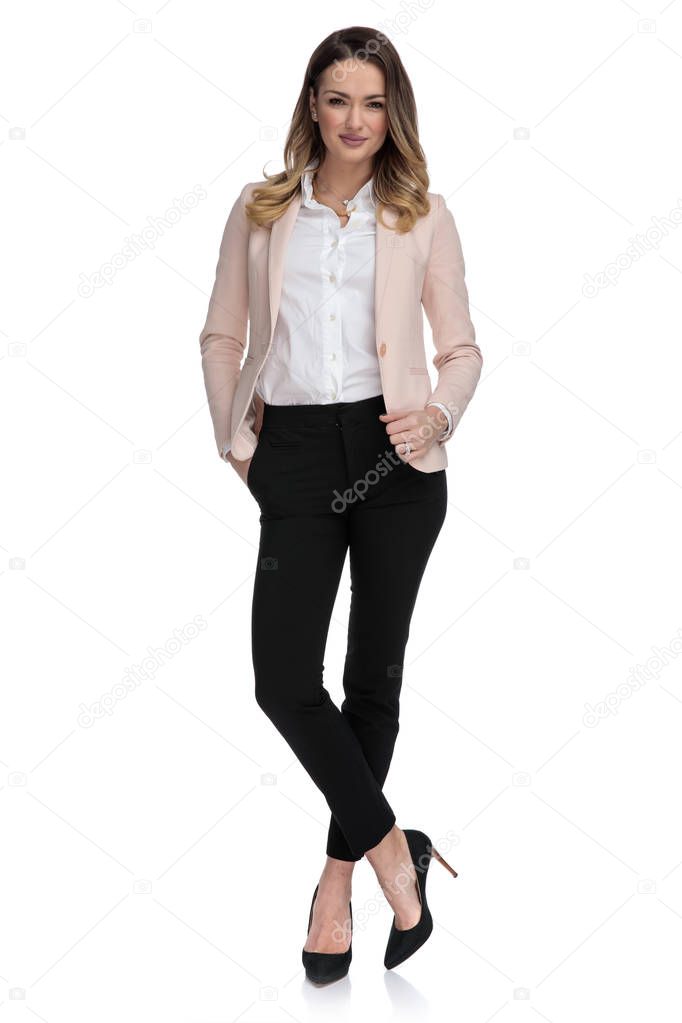 blonde businesswoman stands on white background cross-legged with hand in pocket, full length picture