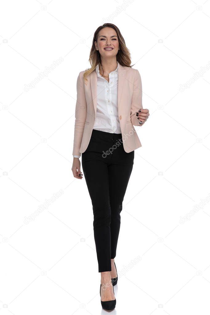 sexy businesswoman wearing pink suit and high heels walking forward and smiling on white background, full body picture