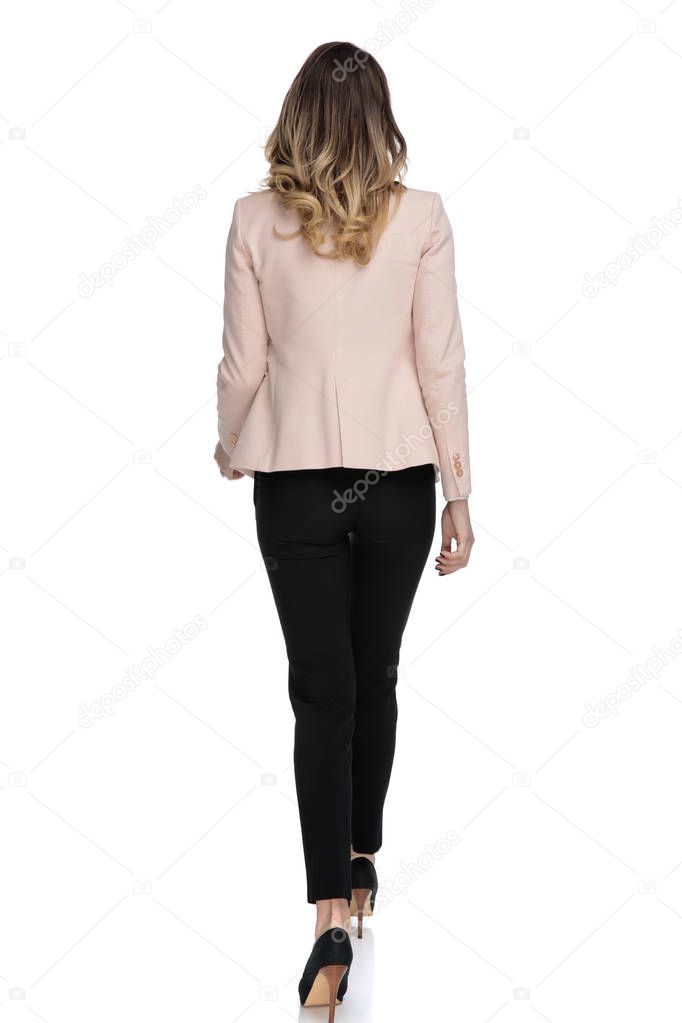rear view of young businesswoman wearing pink suit stepping on white background, full body picture