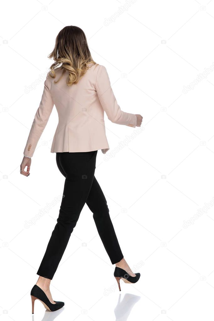 back view of confident businesswoman walking to side on white background, full body picture
