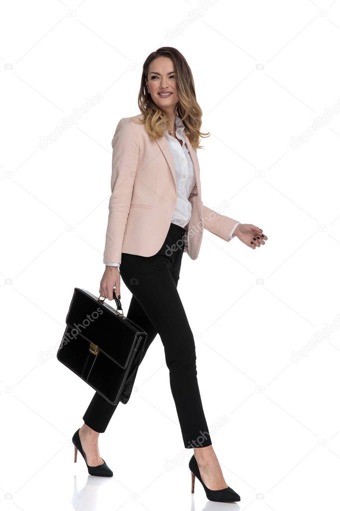 sexy businesswoman holding briefcase walks and looks to side on white background, full length picture