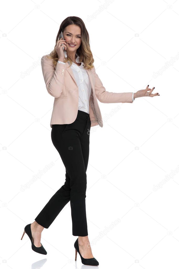 businesswoman talking on the phone walks on white background and presents to side, full body picture