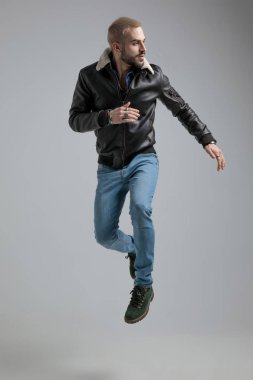 erkek deri ceket ve atlama ve uzak gri arka plan üzerinde seyir kot pantolon yan görünüm