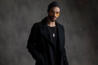 Çekici bir adam modern giysiler ve onun cebinde bir el ile ayakta tonları bir çift giyiyor