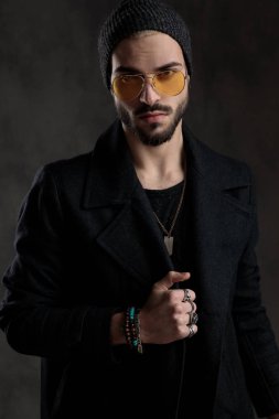 Gri bir arka plan üzerinde dört gözle eliyle ceketini tutan adamı tahrik